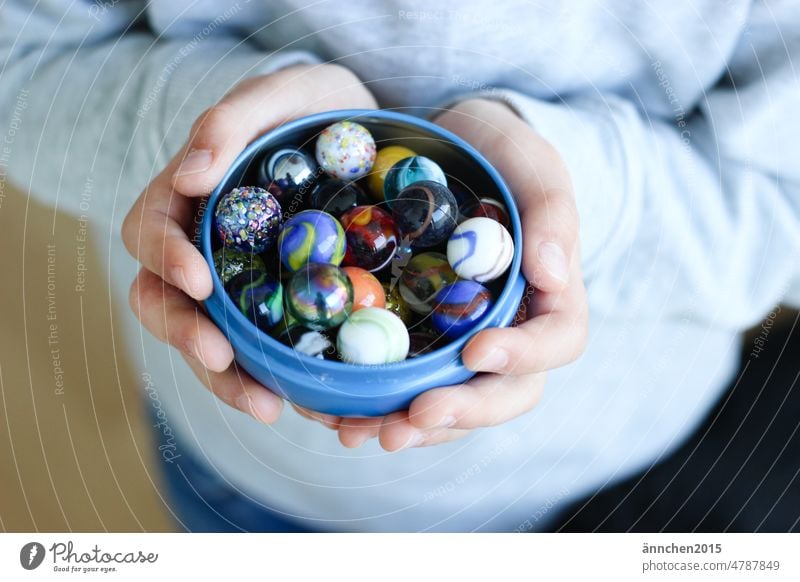 Ein Kind hält eine Schale mit bunten Murmeln Kindheit spielen Spaß Junge Freizeit & Hobby Spielen Kinderspiel Spaß haben Farbfoto Mensch Kleinkind