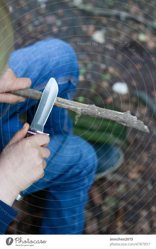 Ein Kind schnitzt einen Stock mit einem Schnitzmesser Messer Wald schnitzen Außenaufnahme Natur Farbfoto Holz Handwerk Umwelt Junge Baumstamm Pflanze Kindheit