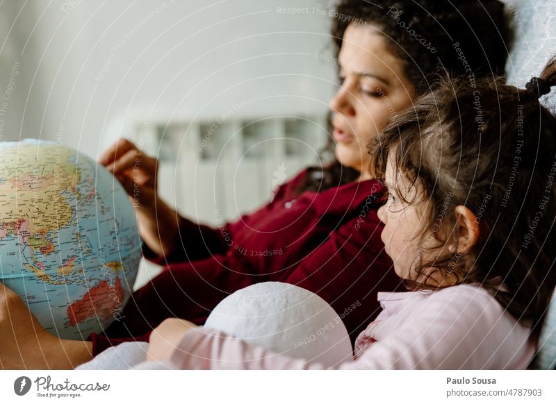 Mutter und Tochter spielen mit dem Erdglobus Erde Erdkugel Globus Ferien & Urlaub & Reisen Planet Kugel Farbfoto blau Geografie Kontinente Globalisierung