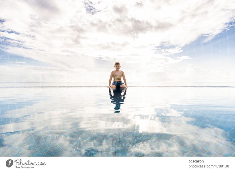 Kleines Kind am Rande eines Schwimmbeckens mit wolkigem Himmel im Hintergrund bezaubernd Bahamas Strandclub blauer Ozean Kaukasier heiter Kindheit Wolken