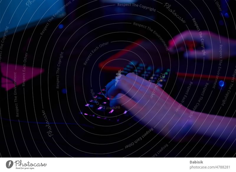 Gamer spielen ein Computerspiel, verwenden eine neonfarbene Tastatur Spiel Keyboard online Spieler cyber dunkel Sucht hintergrundbeleuchtet Spielen Licht RGB