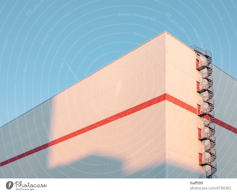 Wendeltreppe an Lagerhalle bei Sonnenaufgang Treppe Fassade Morgen ästhetisch Industrieanlage Außenaufnahme Lagerhaus modern rot orange Morgendämmerung