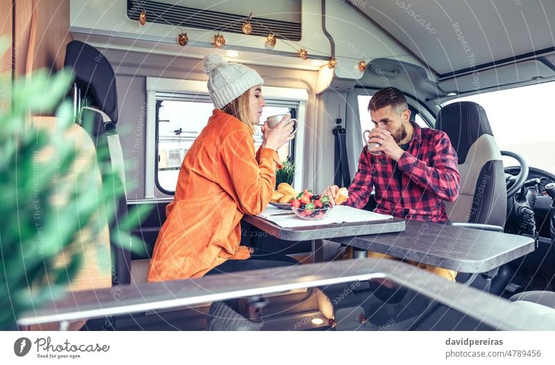 Freunde beim Frühstück im Wohnmobil Kleintransporter Mann Frau trinken Tasse Kaffee Morgen Brötchen Essen Frucht Gesundheit Blaubeeren Erdbeeren