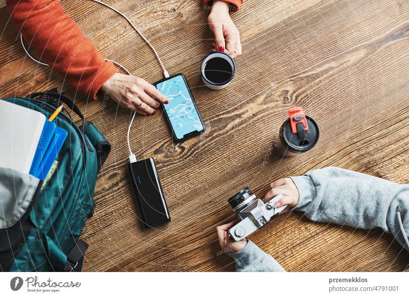 Familie plant Urlaubsreise. Frau sucht Reiseziel und Routen mit Navigationskarte auf dem Mobiltelefon. Aufladen des Smartphones mit einer Powerbank. Nutzung von Technologie auf Reisen