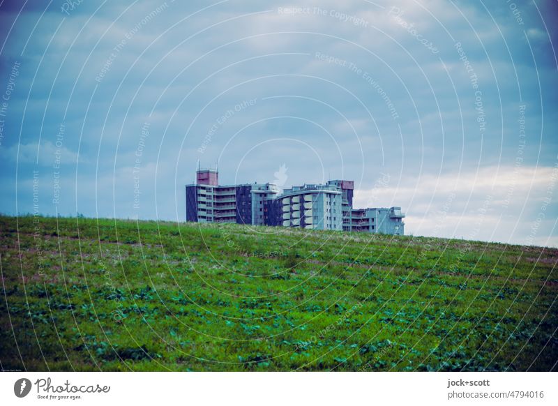 Stadtrandsiedlung, grüner Hügel und blaue Wolken Wohnhochhaus unwirklich Wiese Umwelt Landschaft Weite Himmel Klima Panorama (Aussicht) Natur schlechtes Wetter