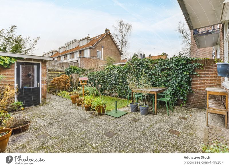 Hinterhof eines Gebäudes mit Pflanzen Terrasse Landschaft Tisch Vorstadt ländlich patio Stil Haus Blumentopf Sommerzeit Außenseite Tür Eingang Fenster Balkon