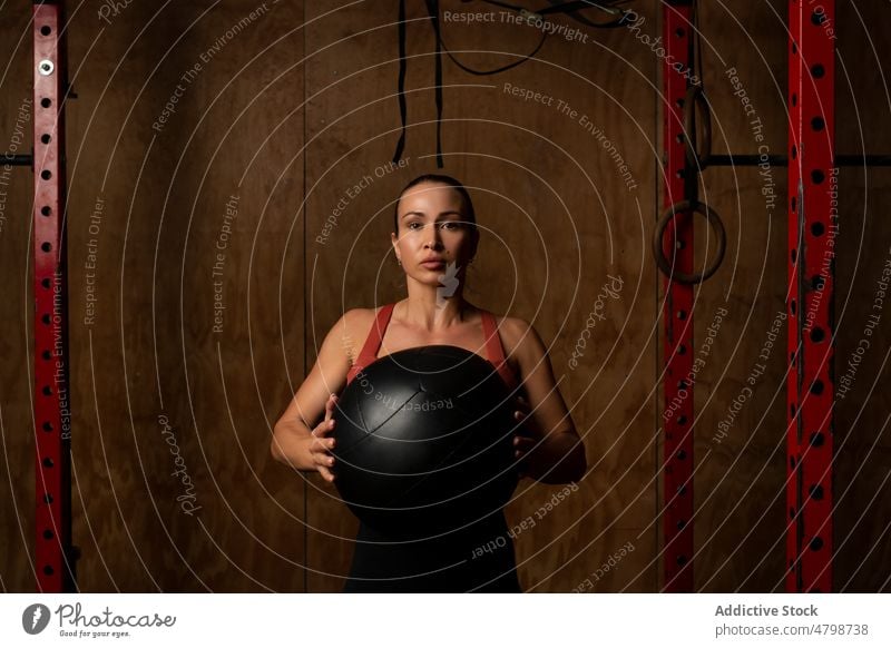 Junge Sportlerin stehend mit Ball im Fitnessstudio Training stark Wohlbefinden Konzentration Übung Frau Wellness passen jung dunkles Haar Sportkleidung