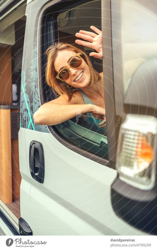 Junge Frau mit Sonnenbrille im Wohnmobil sitzend Glück jung winkend Kleintransporter Sitzen Spaß Hand Sommer Ausflug reisen Reise Fenster Fahrzeug Freiheit 20s