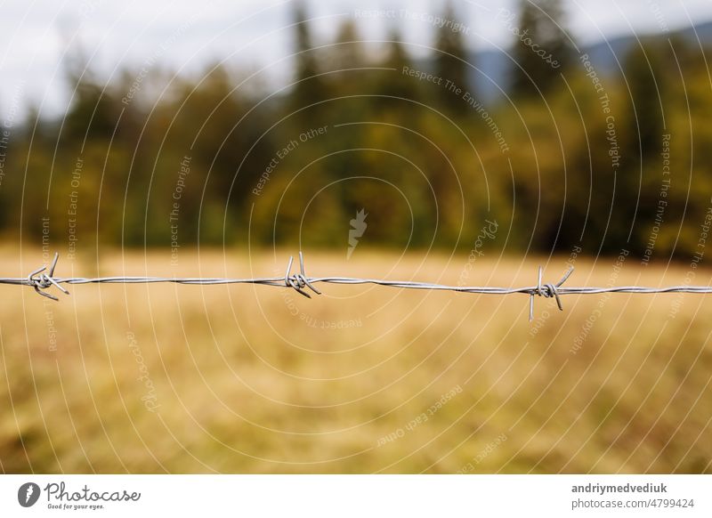 Eine Nahaufnahme eines Stacheldrahtes mit einem Berg im Hintergrund Metall Stahl Draht Sicherheit mit Stacheln versehen Zaun Himmel stechend Gefahr Schutz Borte