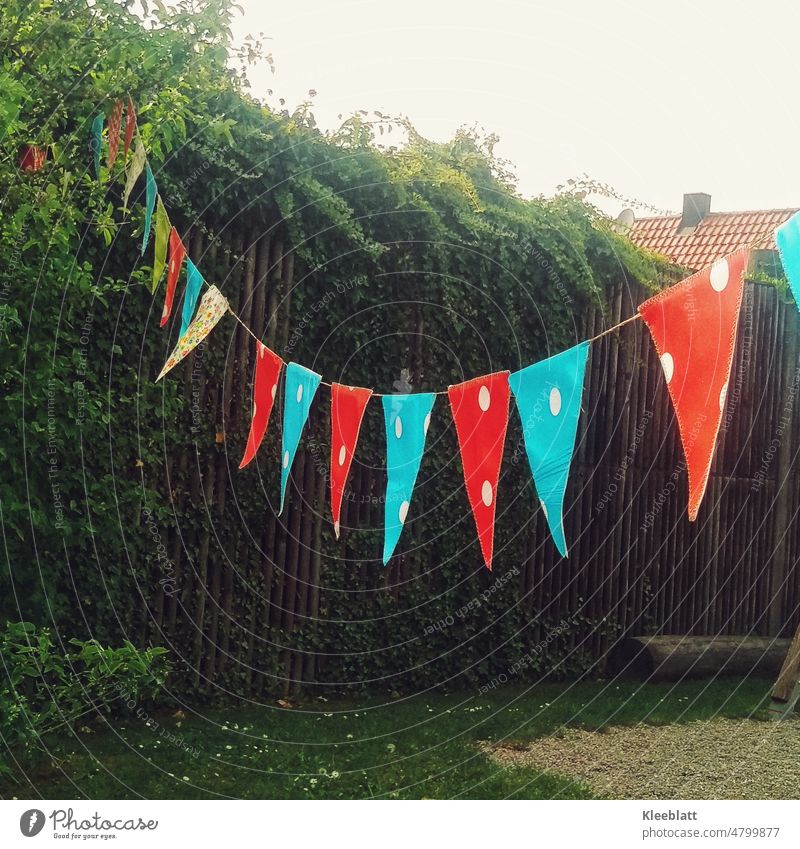 Bunte Wimpel für ein Fest gespannt im Garten zu einer großen Holzmauer mit Grün bunt Feste & Feiern Wimpelkette Fröhlichkeit Veranstaltung