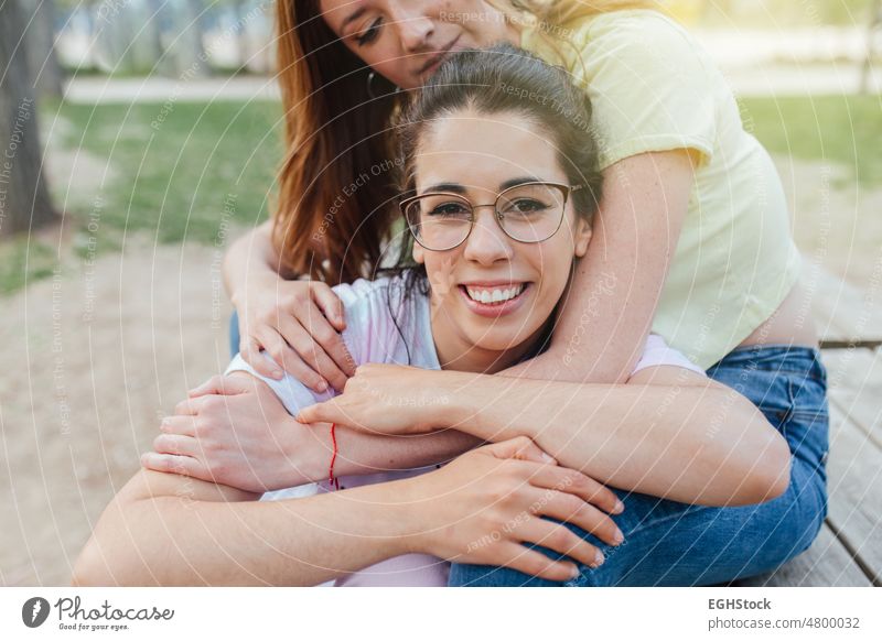 Nahaufnahme von zwei glücklichen Freundinnen, die sich umarmen und lächelnd in die Kamera schauen abschließen zwei Personen Freunde umarmend Lächeln Fotokamera