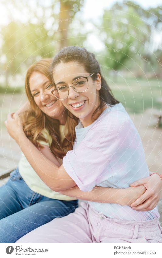 Zwei glückliche Freundinnen umarmen sich und schauen lächelnd in die Kamera zwei zwei Personen Freunde umarmend in die Kamera schauen Lächeln Fotokamera Brille