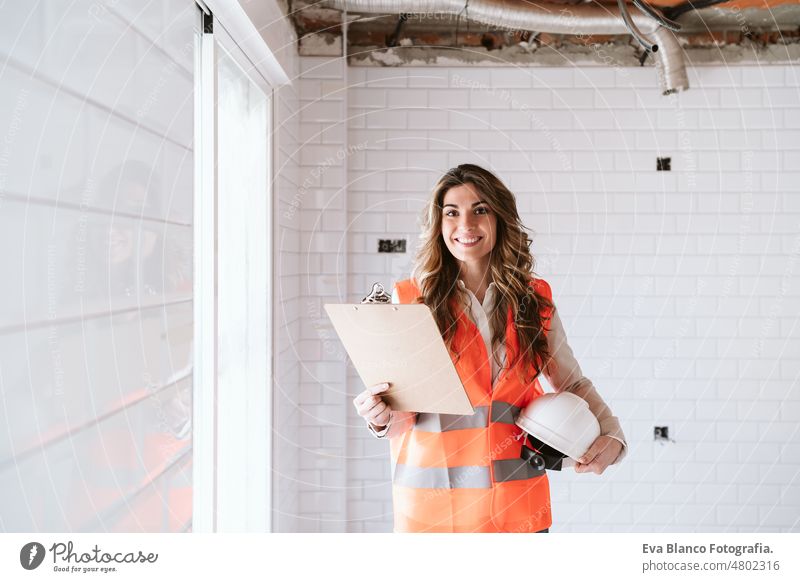 Inspektorin oder Architektin, die eine Küche auf der Baustelle überprüft. Heimwerken Porträt Frau Blaupausen Arbeitsbereich Schutzhelm Schutzmantel Handy