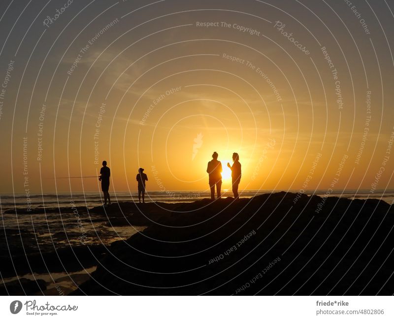 Menschen am Strand vor Sonnenuntergang Meer Spanien Andalusien Silhouette Wasser Felsen Angeln Wolken orange blau Atlantik Costa de la Luz Männer Frauen