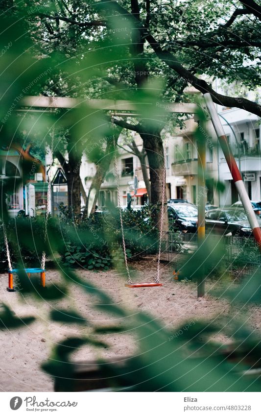 Leere Schaukel auf dem Kinderspielplatz leer Spielplatz verlassen Einsamkeit draußen Menschenleer trostlos Kindheit verwaist Gebüsch einsam niemand