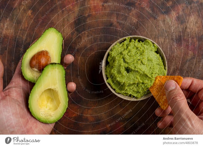 Traditionelle lateinamerikanische mexikanische Sauce Guacamole in Tonschüssel, geschnittene halbe Avocado und Avocado-Sandwiches auf dunklem Hintergrund. Ansicht von oben