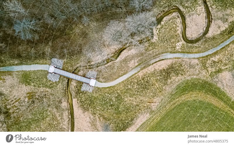 Luftaufnahme im Frühling mit einem Pfad und einem gewundenen Fluss Gras natürlich Farbe Brücke friedlich Natur Wasser Tag Schönheit Hintergrund Bäume Bach wild