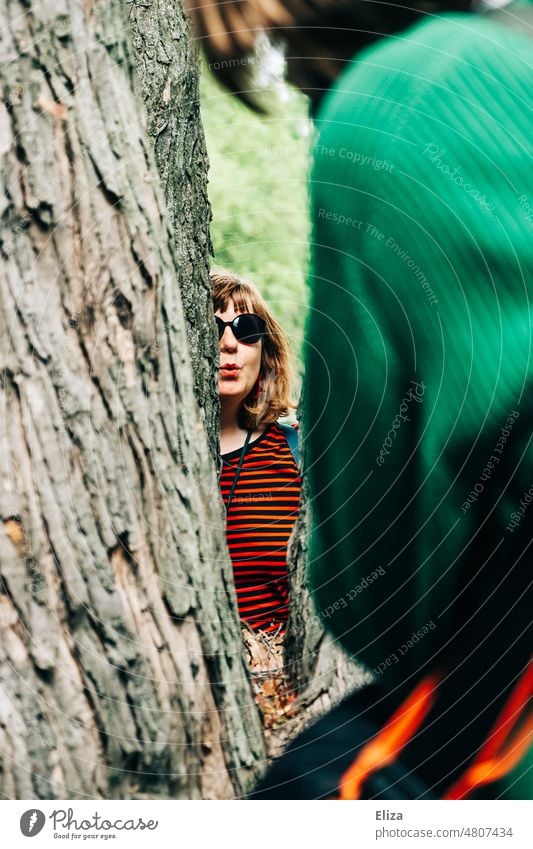 [hansa BER 2022] Frau hinterm Baum macht Kussmund Naturverbunden Baumstamm Baumkuscheln weiblich Frühling Sonnenbrille positiv Freude Mensch Sommer rotblond