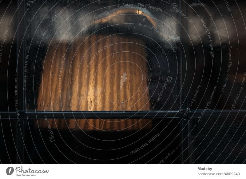 Tischleuchte mit Lampenschirm in Beige hinter altem braunen Fensterglas eines Gasthaus und Restaurant in den Gassen der Altstadt von Münster in Westfalen im Münsterland