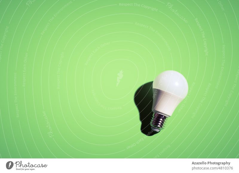 Weiße Glühbirne auf grünem Hintergrund unter dem hellen Licht mit schwarzem Schatten. Knolle elektrisch Wirtschaft weiß Minimalismus Stillleben einfach kreativ