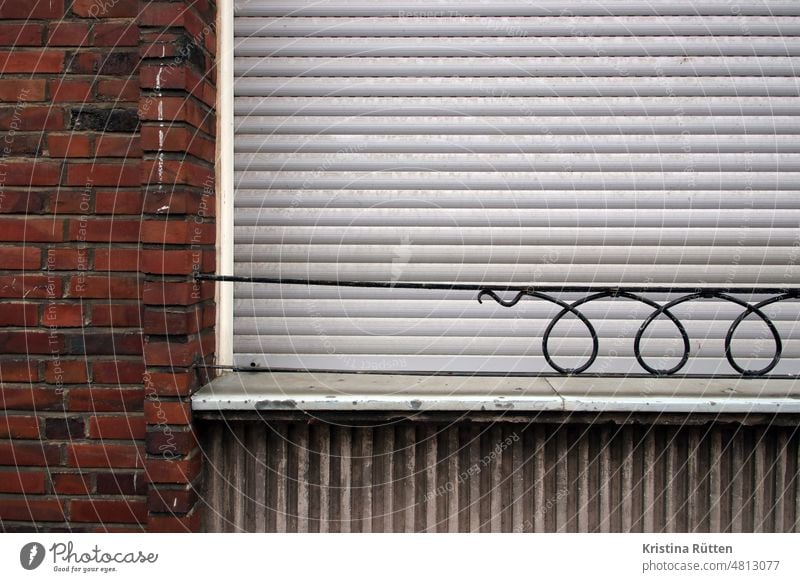 ausrufezeichen an der backstein fassade neben einem geschlossenen rollladen fenster rollo jalousie verschlossen zu fensterbrett backsteine ziegelsteine geländer