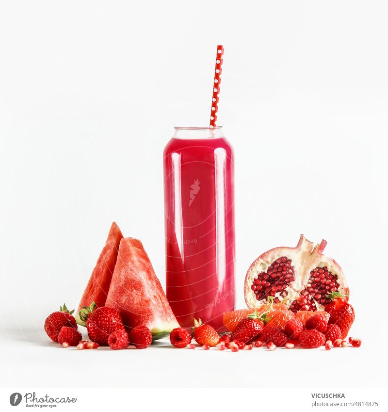 Roter Smoothie im Glas mit Trinkhalm auf weißem Hintergrund mit Fruchtzutaten rot weißer Hintergrund Zutaten Wassermelone Granatapfel erdbeeren Himbeeren