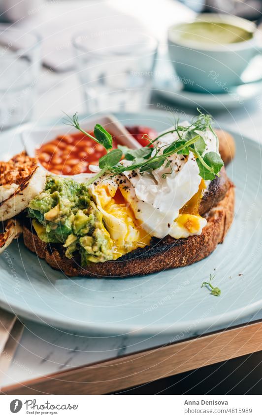 Gesundes Frühstück aus pochierten Eiern und Gemüsen Zuprosten pochierte Eier Avocado Vegetarier Gesundheit Lebensmittel Eigelb Belegtes Brot gegrillter Halloumi