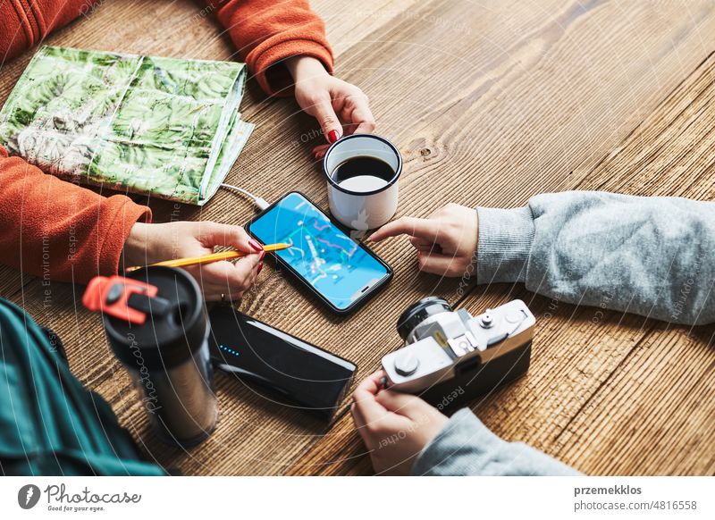 Familie plant Urlaubsreise. Mädchen sucht Reiseziel und Routen mit Navigationskarte auf dem Mobiltelefon. Aufladen des Smartphones mit einer Powerbank. Nutzung von Technologie auf Reisen