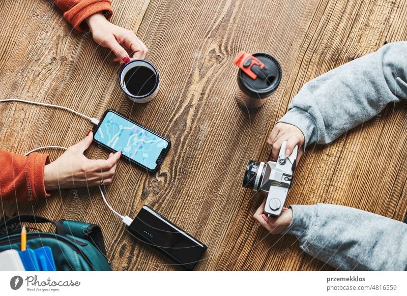 Familie plant Urlaubsreise. Frau sucht Reiseziel und Routen mit Navigationskarte auf dem Mobiltelefon. Aufladen des Smartphones mit einer Powerbank. Nutzung von Technologie auf Reisen