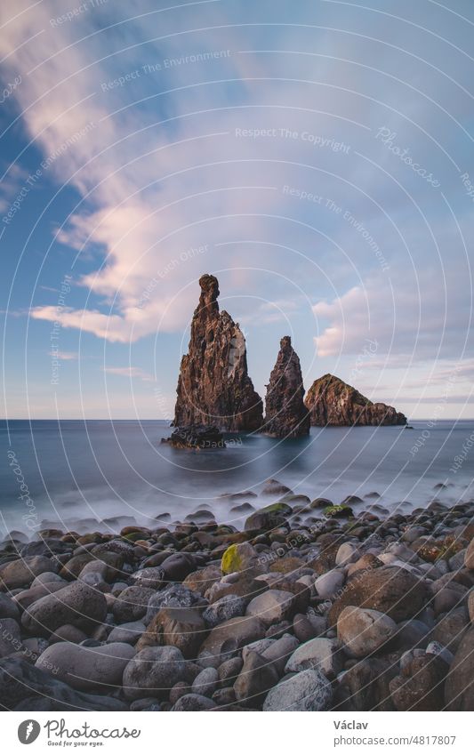 Der magische Ort Ilheu da Ribeira da Janela in der Nähe der berühmten Stadt Porto Moniz im Nordwesten der Insel Madeira, Portugal. Langzeitbelichtung bei Sonnenuntergang auf einem vom Meer umspülten Felsen