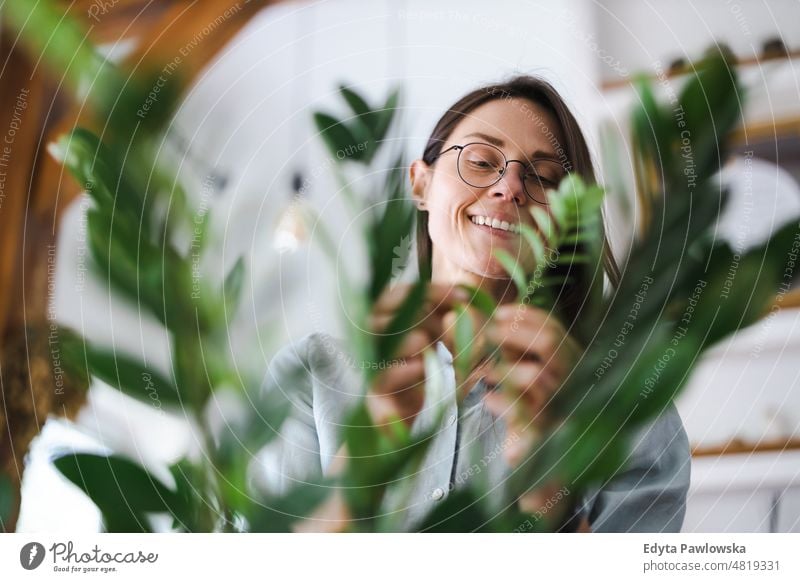 Junge Frau, die sich um ihre Zimmerpflanzen kümmert eingetopft Pflege grün Natur Blätter Frische Hobby wachsen Blumentopf Gartenarbeit frisch Blumenhändler