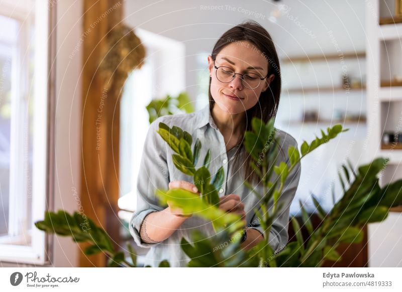 Junge Frau, die sich um ihre Zimmerpflanzen kümmert eingetopft Pflege grün Natur Blätter Frische Hobby wachsen Blumentopf Gartenarbeit frisch Blumenhändler