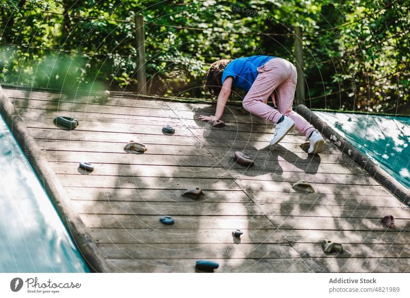 Anonymes Kind übt Klettern an der Wand auf dem Spielplatz Mädchen Aufstieg Park Felsbrocken Training Aktivität üben Hobby extrem aktiv Kindheit Übung Natur