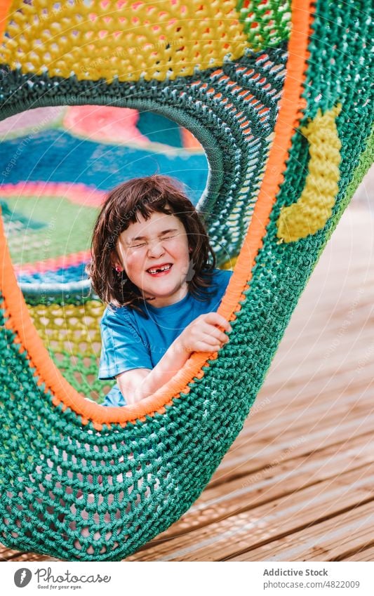 Glückliches niedliches Kind mit geschlossenen Augen im Inneren der bunten Hängematte liegend sich[Akk] entspannen Augen geschlossen Park genießen Mädchen