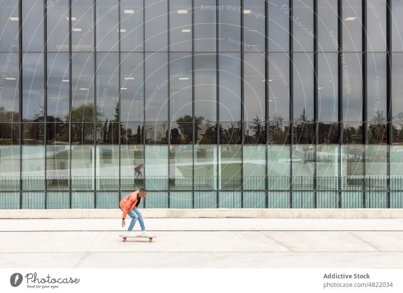 Cooler junger schwarzer Mann fährt Skateboard auf einer modernen Stadtstraße Mitfahrgelegenheit Straße Gebäude trendy Großstadt cool Skater Aktivität Stil