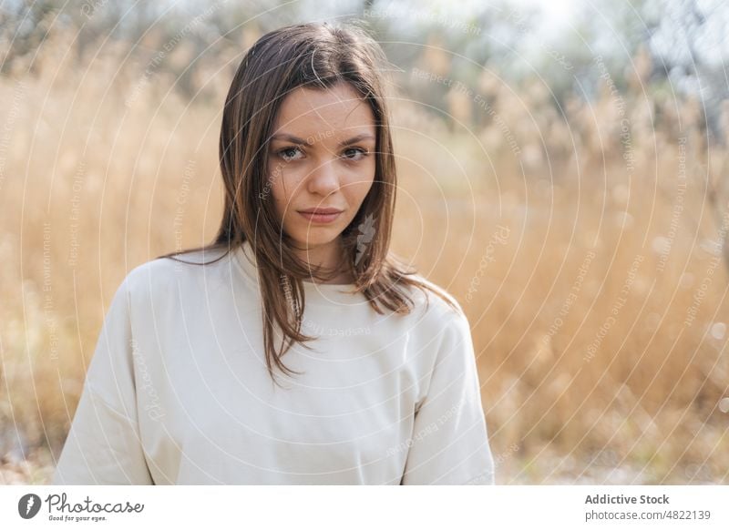 Ruhige Frau steht in ländlicher Umgebung und schaut in die Kamera Wiese selbstbewusst Natur Landschaft Model Stil Porträt feminin Windstille Vorschein Feld jung