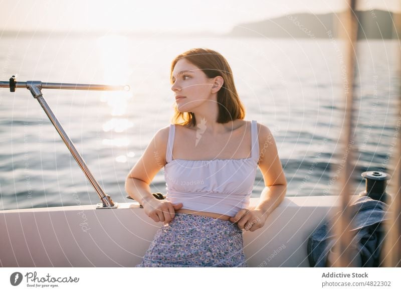 Ruhige junge Frau bewundert die Natur, während sie auf einem Segelboot sitzt MEER Jacht bewundern Feiertag Kreuzfahrt Sommer Urlaub Porträt sitzen trendy Stil