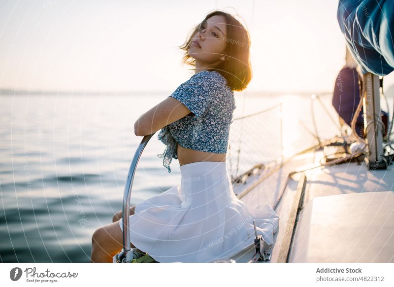 Stilvolle weibliche Touristin, die sich auf einer Jacht ausruht und den Sonnenuntergang über dem Meer bewundert Frau bewundern MEER Segelboot Reisender Urlaub