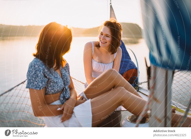 Glückliche Frauen unterhalten sich während einer Kreuzfahrt auf dem Meer bei Sonnenuntergang Segelboot Freund MEER Sommer Urlaub Zusammensein Jacht Lächeln