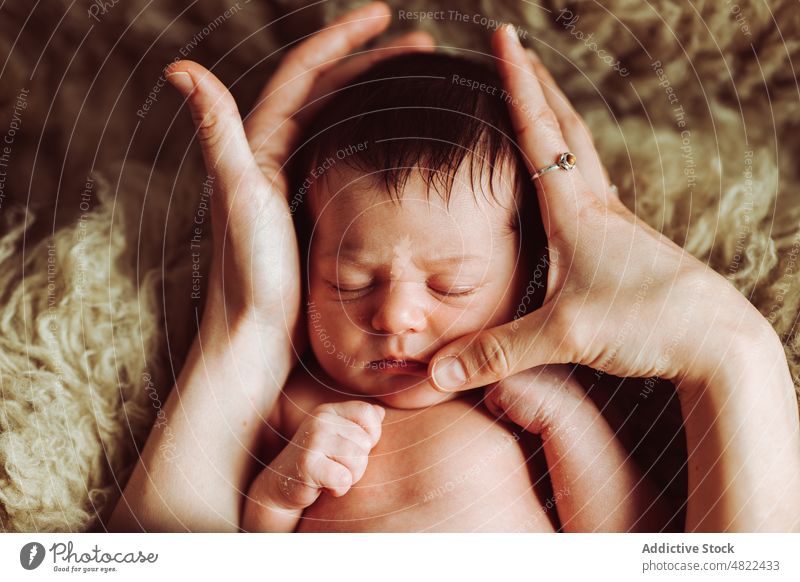 Crop Eltern streicheln liebenswert schlafendes Baby Augen geschlossen Streicheln Liebe Lügen neugeboren bezaubernd die Faust ballen unschuldig Zusammensein Bett