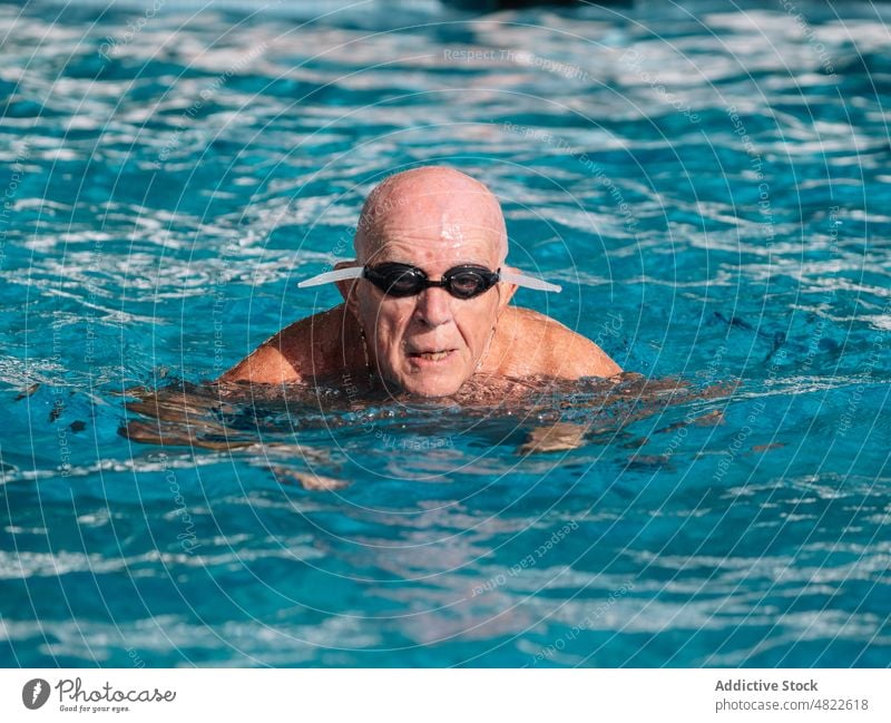 Älterer Mann mit Schwimmbrille schwimmt im Pool an einem sonnigen Tag schwimmen Feiertag aktiv Urlaub Sommer Schutzbrille älter Senior Porträt Gesundheit üben