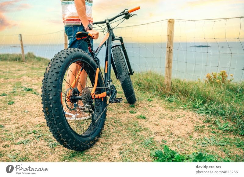 Fat Bike am Strand mit einem Mann, der es hält Fatbike Küste unkenntlich Typ Beteiligung MEER Person Sport Textfreiraum Stehen Fahrrad Lifestyle Zyklus