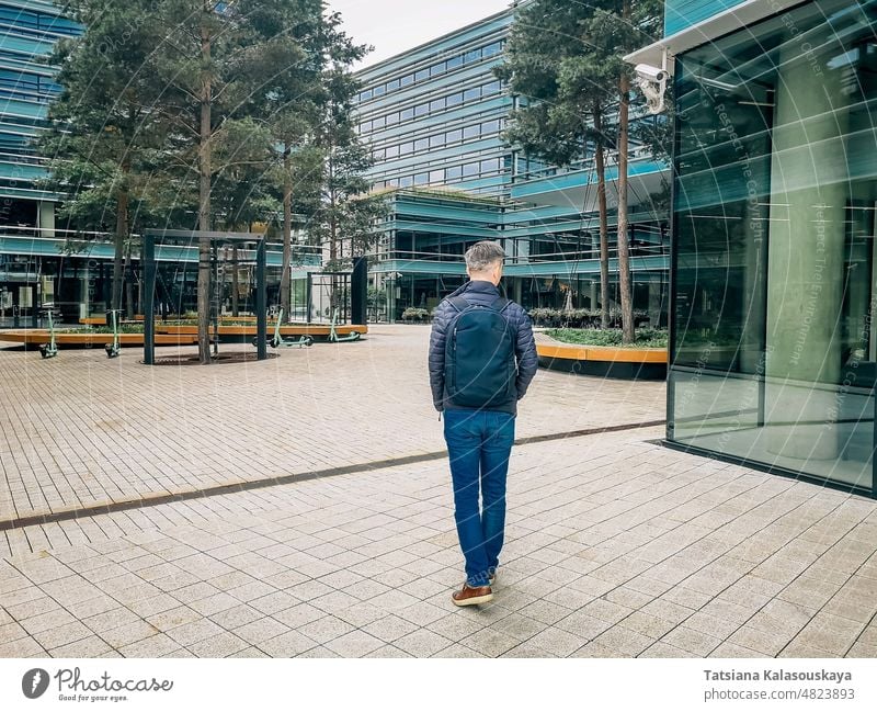 Ein Mann geht zur Arbeit in einem modernen Viertel männlich Typ Menschen Person Kaukasier Lebensstile Jeanshose Jacke blau Rucksack Laptop-Rucksack gehen Sie