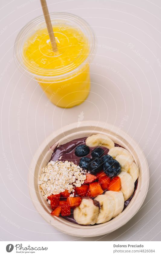 Ein Teller mit geschnittenen Früchten wie eine Acai-Schale, begleitet von einem natürlichen Saft acai Mandelbutter Mandeln Hintergrund Beeren Blaubeeren