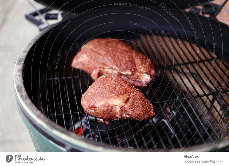 Zwei Stück gewürztes Rindfleisch auf einem runden, grünen Kamado- Grill zu Grillbeginn Fleisch Essen Food Kamadogrill Kamado Grill Big Green Egg