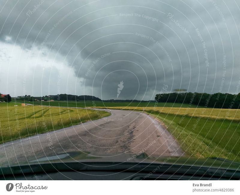 herannahendes Unwetter am Horizont Starkregen Starkregenwolke Gewitterzelle Klima Landstraße Kurve Außenaufnahme Menschenleer Gefahr Unwetterwarnung