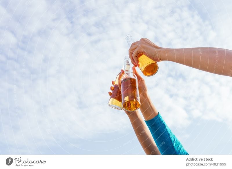 Unbekannte Freunde stoßen unter blauem Himmel an Zuprosten Strand MEER Bier Flasche Arm angehoben Blauer Himmel Hände Wochenende Sommer Mann Frauen Ernte ruhen