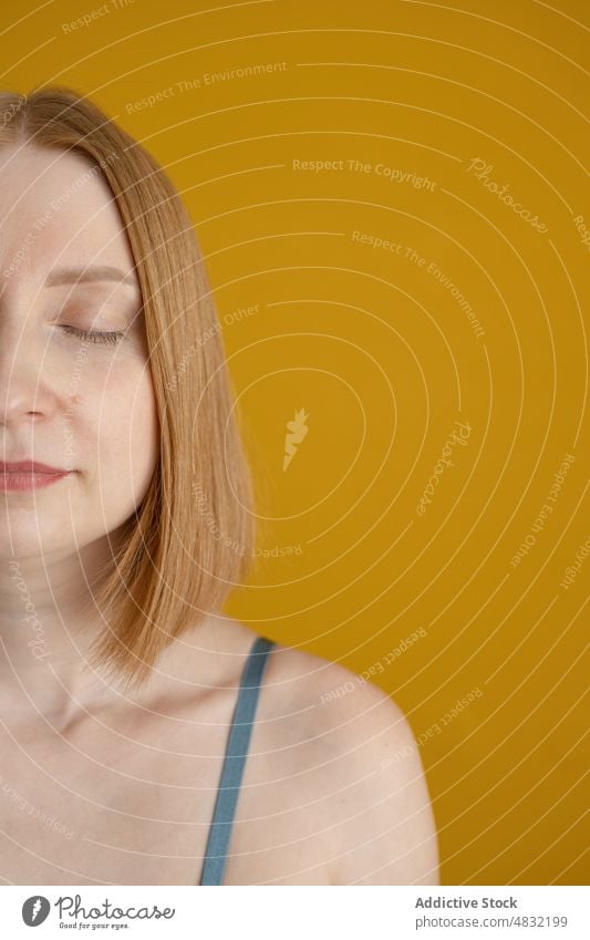 Crop ruhige junge Dame mit geschlossenen Augen in gelben Studio Frau Augen geschlossen Windstille Model Porträt Persönlichkeit friedlich feminin Erholung