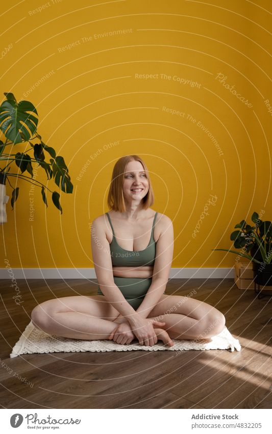 Glückliche Frau sitzt in Padmasana-Pose und lächelt während einer Yoga-Sitzung Lotus-Pose padmasana Lächeln positiv Wellness Gesunder Lebensstil Asana