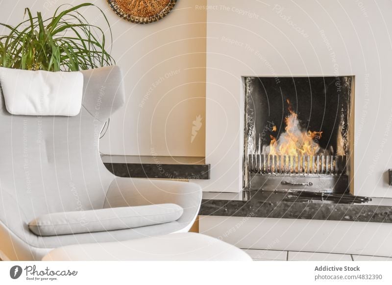 Gemütliche Wohnzimmerdetails mit weichem Sessel und Kamin Armsessel Feuerstelle Villa Innenbereich Komfort Möbel Dekor wohnbedingt modern Stil eingetopft